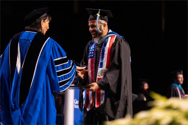   A graduate reacts to receiving their diploma. 