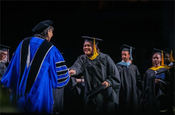  A graduate shakes the hand of the university president after receiving their diploma.