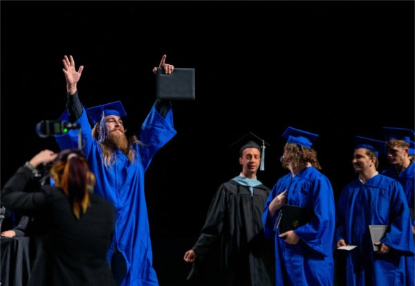   A graduate reacts to receiving their diploma. 