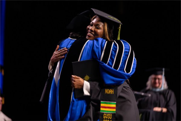   A graduate reacts to receiving their diploma with a hug. 