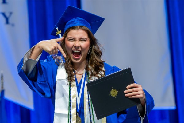   A graduate reacts to receiving their diploma. 