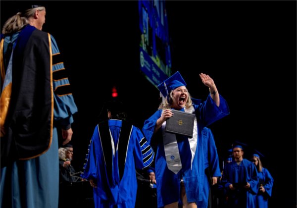   A graduate reacts to receiving their diploma. 