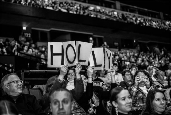  People in the audience hold up a sign that shows the letters to spell HOLLY. 