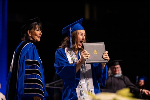   A graduate reacts to receiving their diploma. 