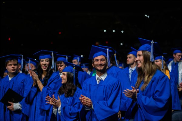  Graduates clap and smile at the end of the commencement ceremony.