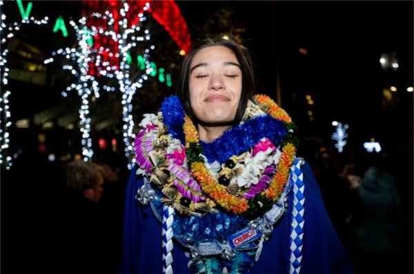  A graduate with their eyes closed relishes the many lei around their neck in honor of the graduation given by family.