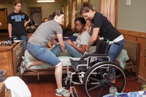 Grand Valley students majoring in occupational therapy help train Indian Trails Camp counselors learn to transfer campers from bed to wheelchair.