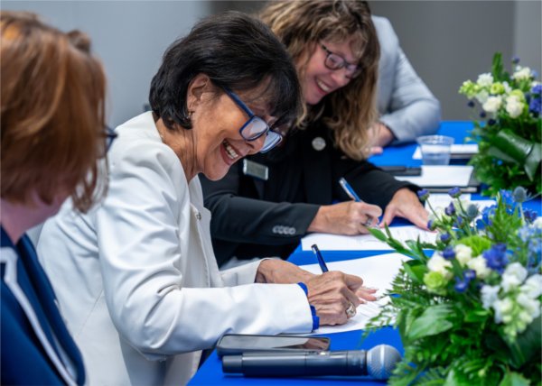 President Philomena V. Mantella signs documents near Starr Commonwealth President and CEO Elizabeth Carey at the DeVos Center for Interprofessional Health in Grand Rapids on Aug. 12. Starr Commonwealth has partnered with GVSU Omni.
