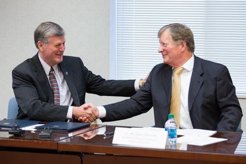 President Thomas J. Haas, left, and Michael Shibler, superintendent for Rockford Public Schools, shake hands and sign an early college agreement April 28.
