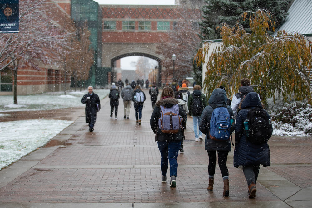 students, staff walking on campus in a light snow