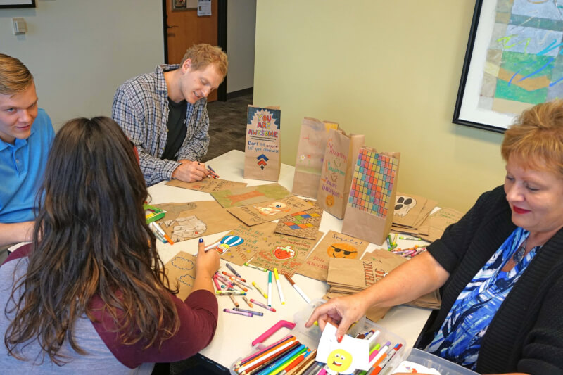 Students, faculty and staff decorate bags for Kids' Food Basket.