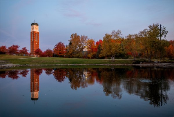 Trees with fall color are also reflected in a pond. The carillon is in the background.