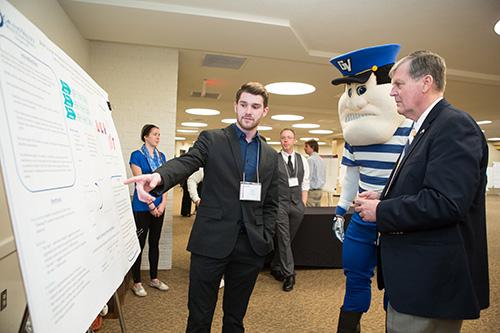 President Thomas J. Haas and Louie the Laker study a poster presentation by a student during 2014's Student Scholars Day. This year's event is set for April 8.